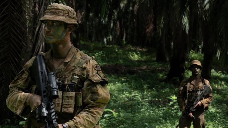 Two Australian soldiers conduct a jungle patrol with weapons.