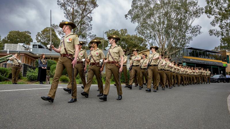 A group of Defence personnel in Army uniforms march along a street.
