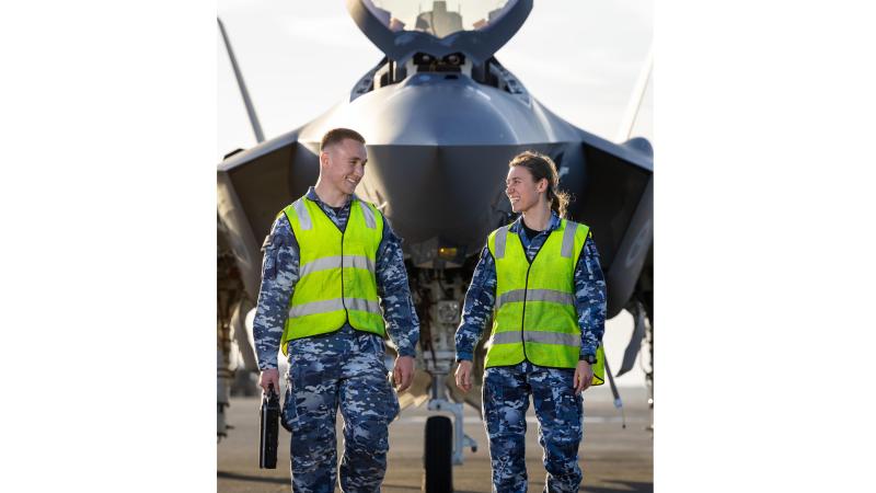 A man and woman in hi-vis and military uniform in front of an aircraft.