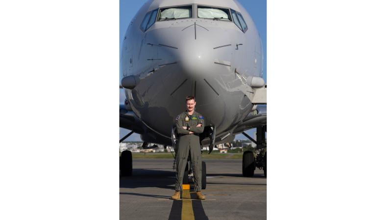A man in military uniform standing before an aircraft.