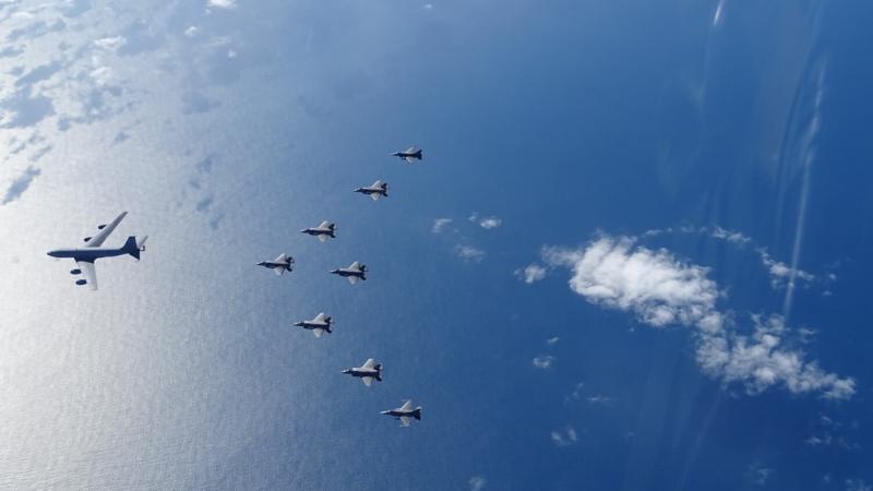 Eight small aircraft fly in formation behind a large aircraft.