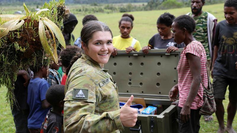 A female soldier gives the 'thumbs up' as Papua New Guinean locals gather to check out newly delivered supplies.