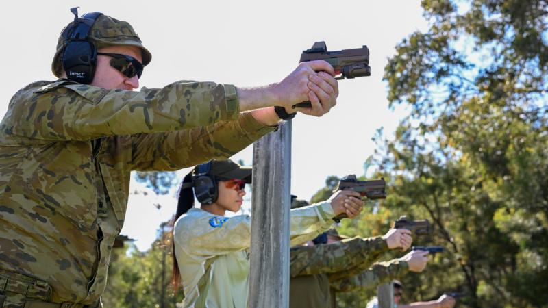 Soldiers and aviators fire pistols during a competition.