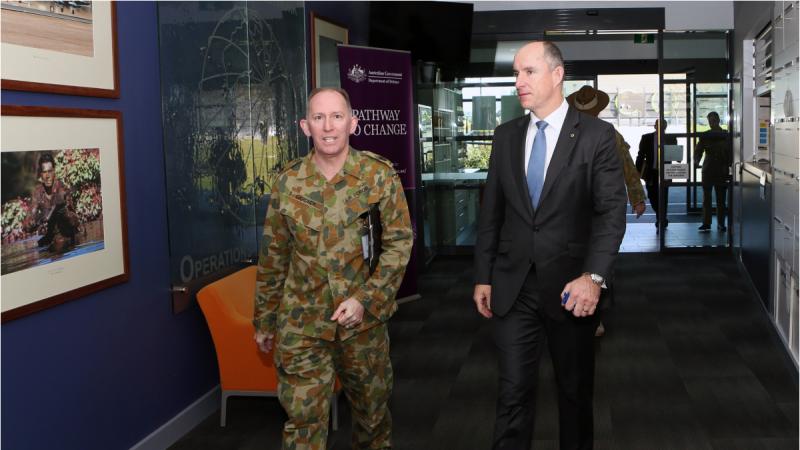 An ADF officer accompanies a civilian through a Defence building in Canberra.