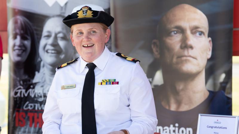 Commodore Katherine Tindall speaking outside a mobile blood donation van.