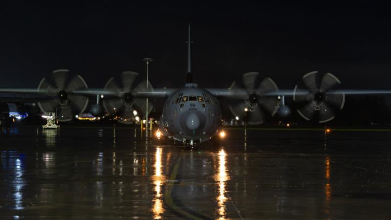 A C-130J Hercules on the tarmac on a rainy night.