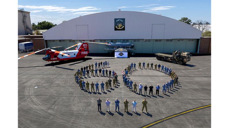 Military members forming the number 60 on at an aircraft hangar.
