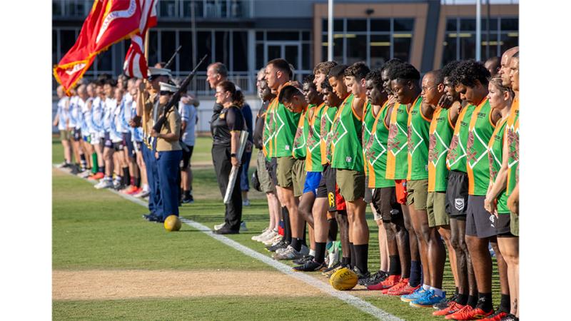 Men in sports uniform stood in line with a flag.