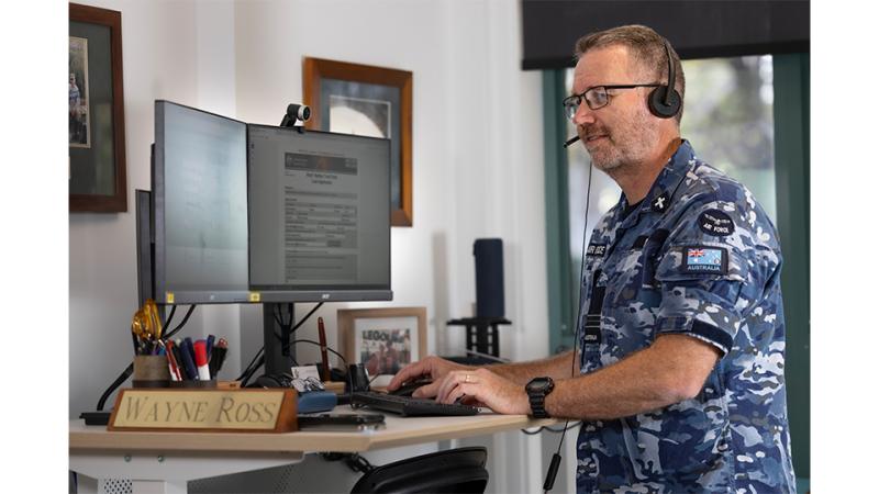 A man in military uniform uses a computer.