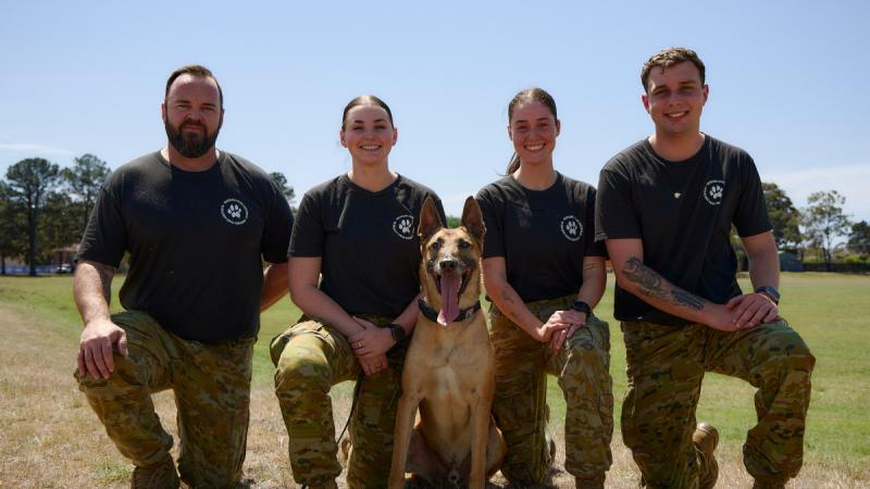 Four military personnel with a dog.