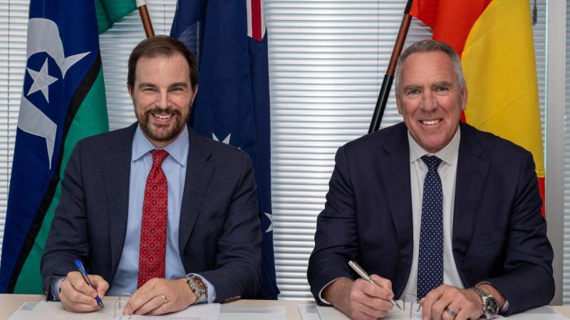 A public servant and business executive sign documents to extend an ADF satellite communications system.
