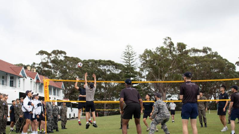 Two people from opposing teams jump at the net during a volleyball game.
