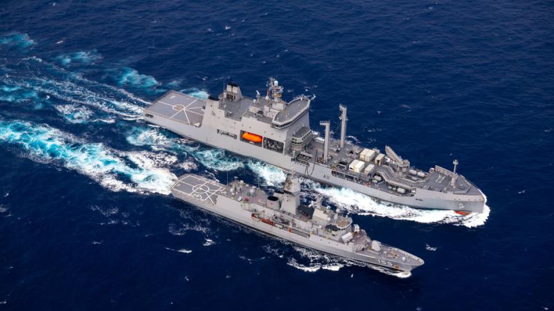 An Anzac-class frigate alongside a Royal New Zealand Navy ship during a replenishment at sea.