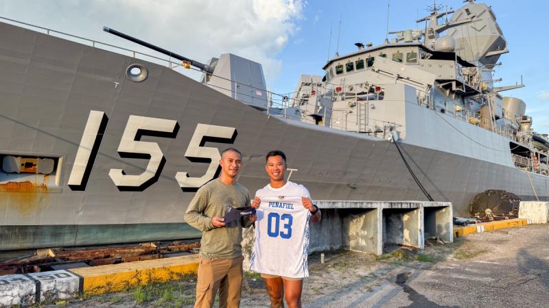 An Australian and a Filipino sailor meet at the wharf in Subic Bay with HMAS Ballarat alongside.