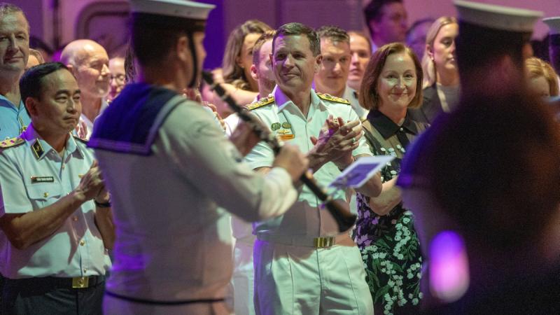 Navy musicians entertain uniformed and civilian guests on board a ship.