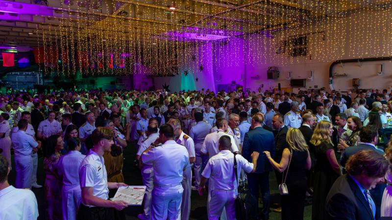 A large crowd of people at a party with fairy lights hanging from the ceiling.
