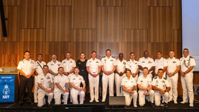 A group of Navy personnel stand on a stage.
