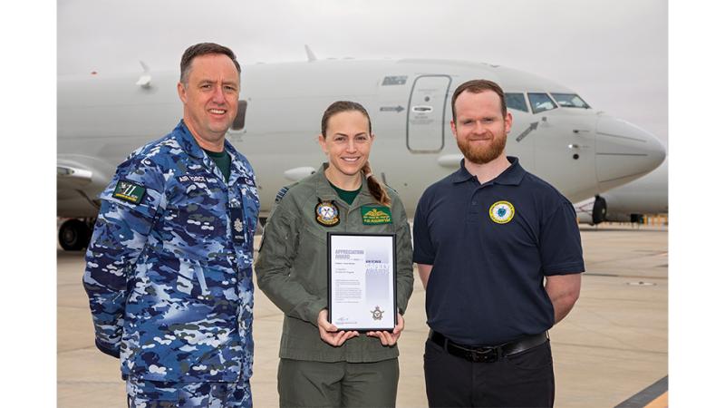 Two military personnel and a civilian with an award. 