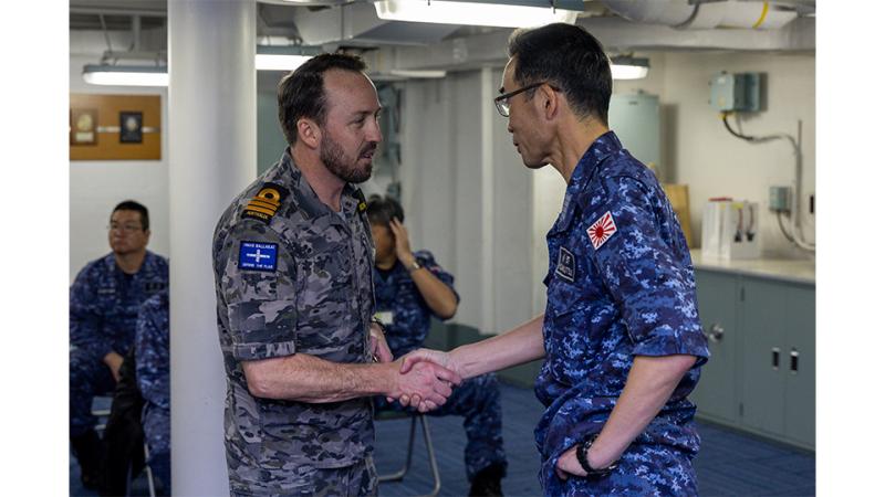 Two men in military uniform shake hands.