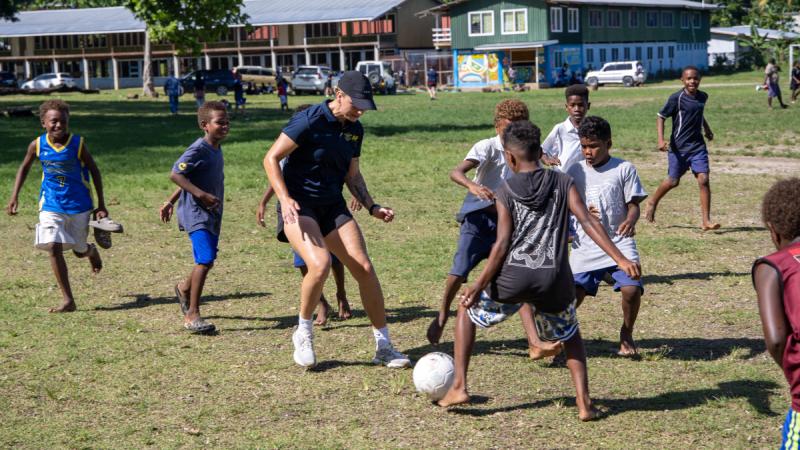 An ADF athlete plays football with children in the Solomon Islands.
