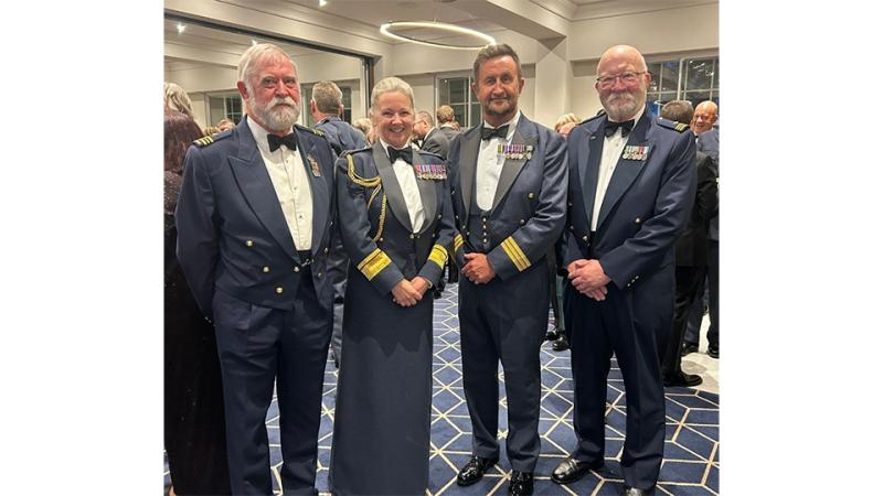 Four people in the dress uniform of the Royal Australian Air Force and the Royal Air Force standing together at an indoor event.