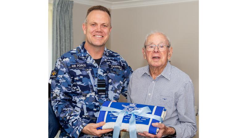 Two men holding a folded quilt.