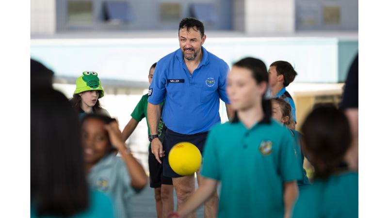 A man and children outside in sports uniform.