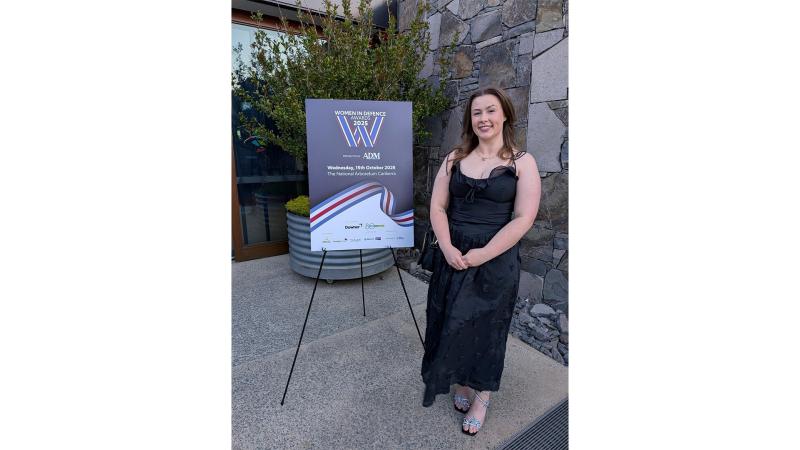 A woman with a sign for the 2025 Women in Defence Awards.