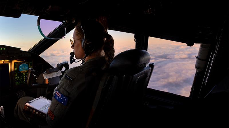 A pilot flying an aircraft at dawn.