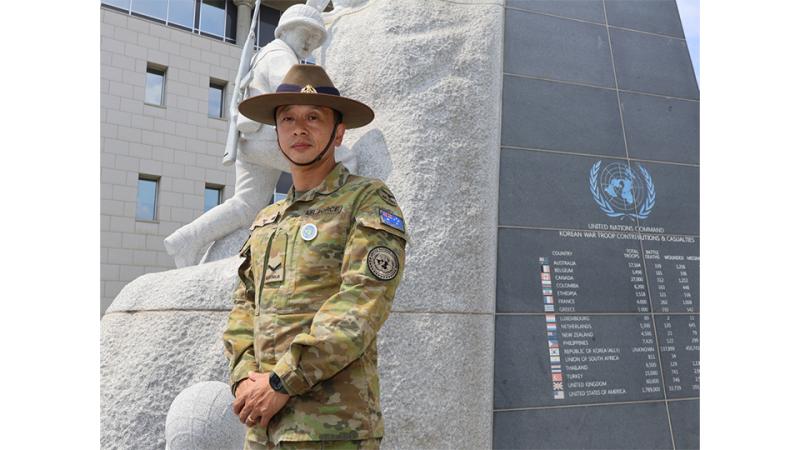 A man in uniform stands in front of a monument.