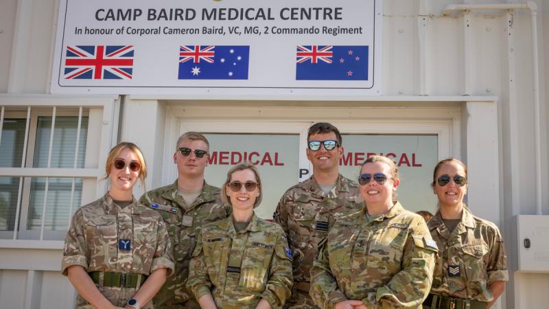 A group of uniformed personnel standing outside a building under a Camp Baird Medical Centre sign.