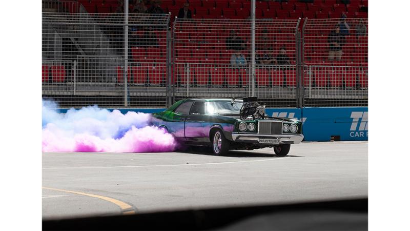 A moving green car emits purple smoke.