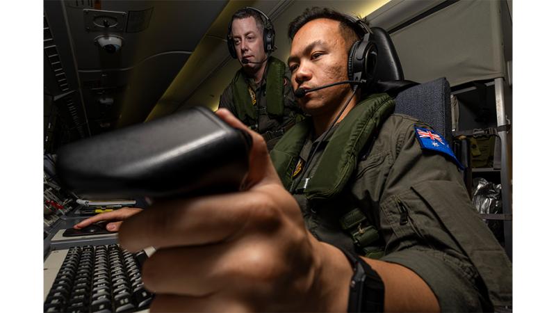 A male military member observes another military member at work.