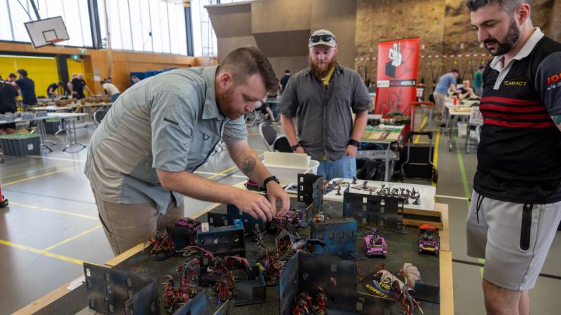 Wargamers gather around a tabletop battle scenario.
