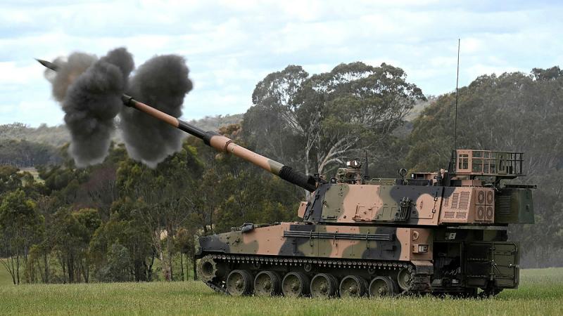 A tank fires a shot in the Australian bush - two black smoke clouds are seen at the front of the tank.