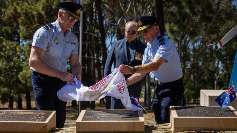 Two Royal Australian Air Force officers unveil the Australian Armourers Association plaque at the RAAF Memorial Grove, Canberra.