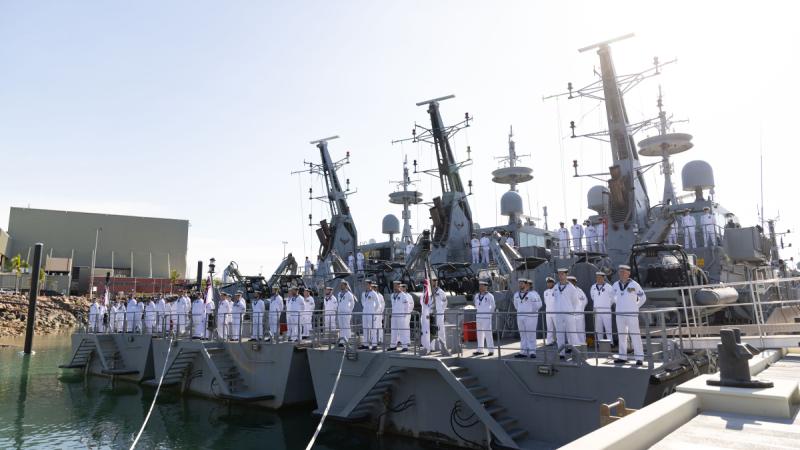Sailors stand in formation on the aft decks of three patrol boats.