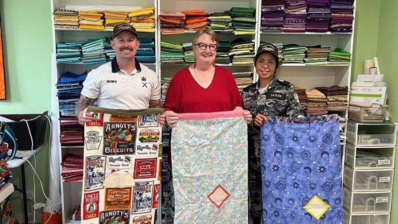 Petty Officer Matthew Rowe, Aussie Hero Quilts CEO Jan Maree Ball and Midshipman Emily Taylor proudly hold Laundry Bags for crew of HMAS Stalwart.