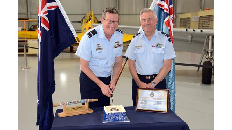 A military member cuts a cake with another member present.
