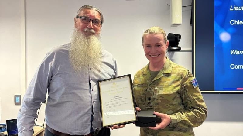 A civilian receives an Australian Public Service Long Service Award from a senior military officer.