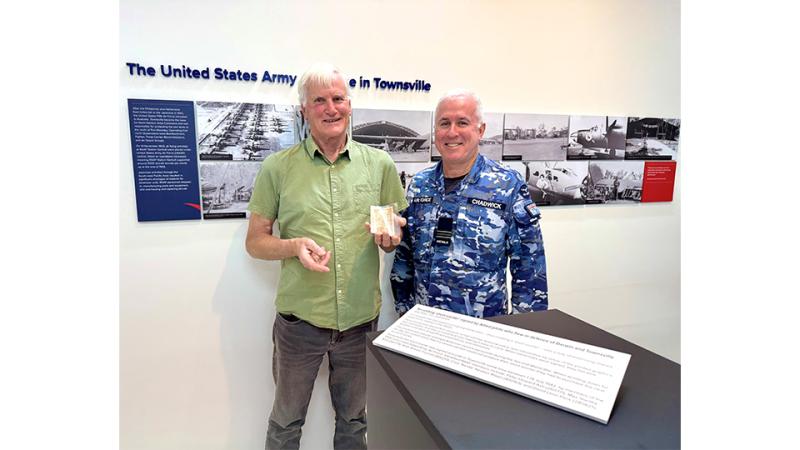 A military man and a civilian holding an old bank note.