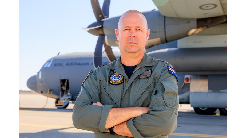 A military member in front of an aircraft on the tarmac.