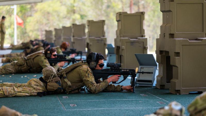 Several soldiers lie prone on a firing line aiming their weapons downrange.