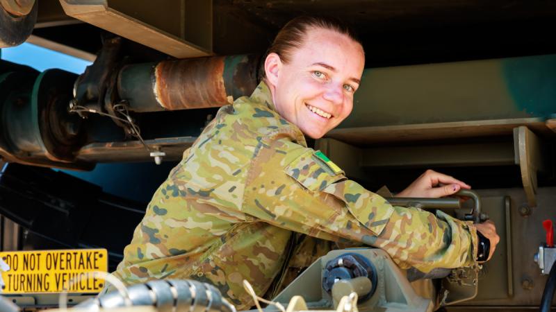 A soldier attaches a trailer to the rear of a large vehicle.