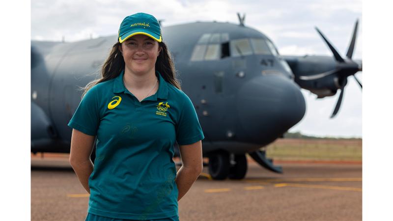 A woman in Australiana uniform stands before an aircraft.
