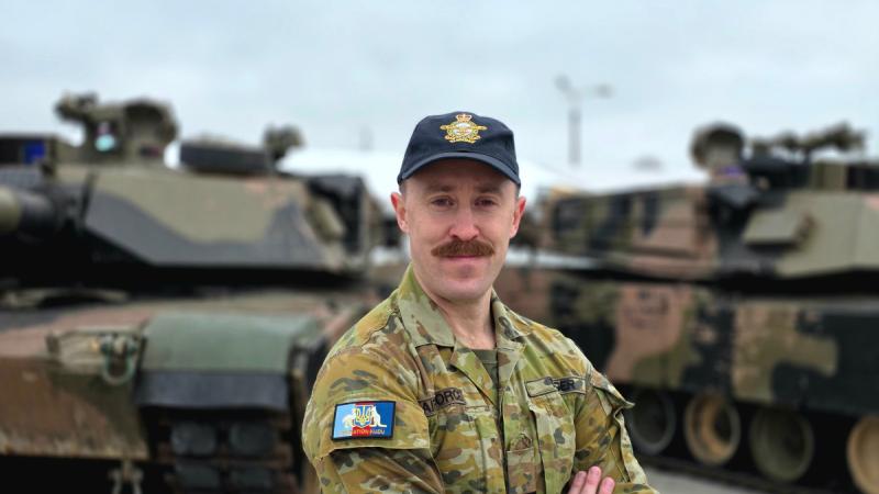 A man in Air Force fatigues stands in front of two tanks.