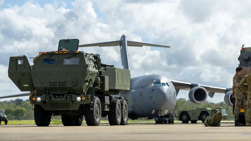 An Australian rocket launcher sits on the tarmac in front of an aircraft. 