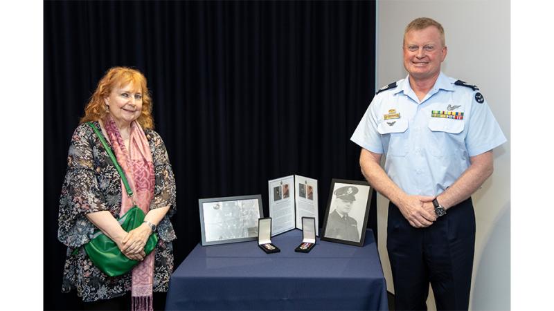 A military member and a civilian display two awards.