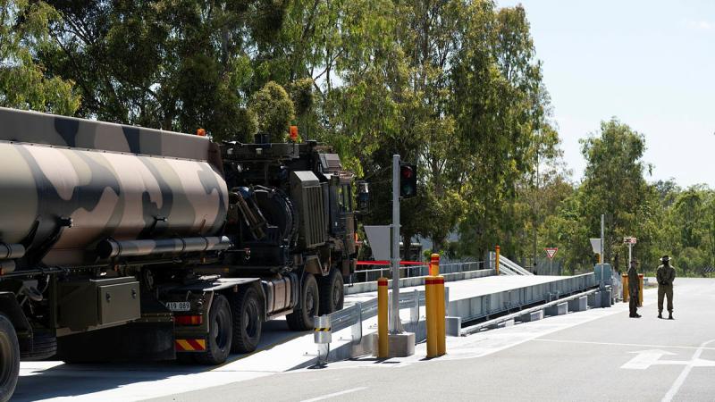 An Army vehicle drives on to a slightly elevated concrete weighbridge.