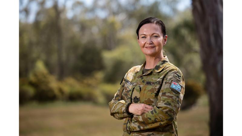 A woman in military uniform standing outside.